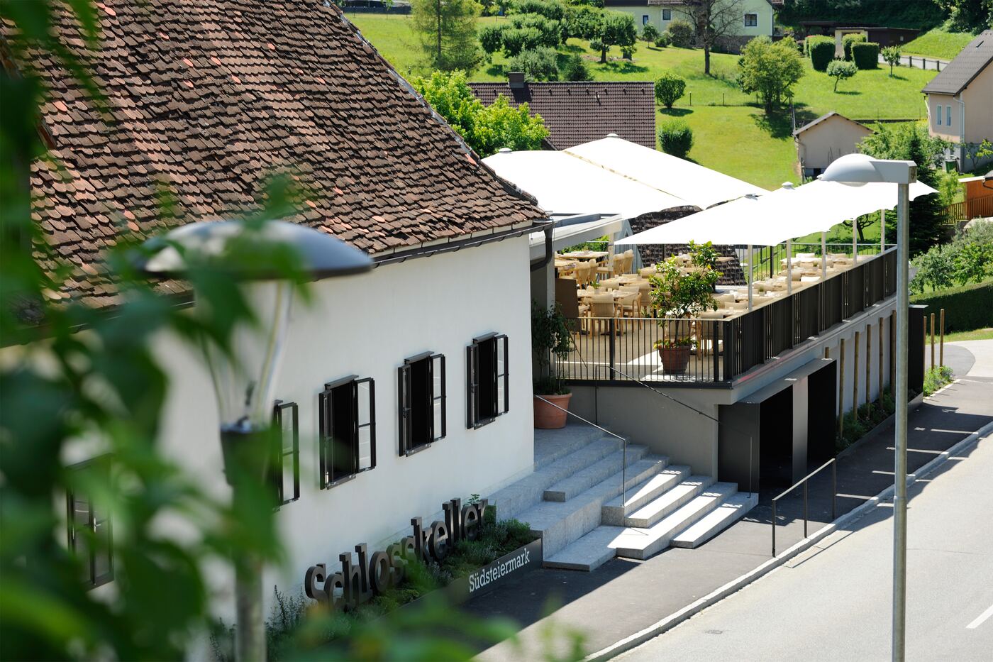 Außenansicht des Schlosskellers Südsteiermark mit Schriftzug, Stiegenaufgang und Terrasse am Seggauberg
